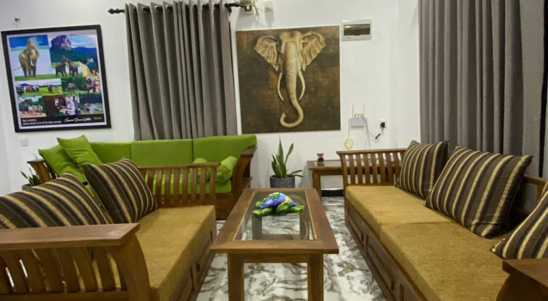 Spacious and inviting living area in Sigiriya Villa, featuring stylish wooden seating and elephant artwork. Ideal place to stay in Habarana.